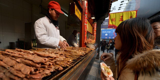 A Chinese hawker barbecues lamb kebabs at his stall in the Wangfujing shopping street of Beijing on February 21, 2013. China is considering a ban on barbecues to help reduce air pollution in built-up areas after heavy smog recently choked large swathes of the country, state media reported. The country's environmental watchdog has issued draft guidelines advising major cities to adopt legislation banning 'barbecue-related activities', risking the ire of street food-loving locals. AFP PHOTO/Mark RALSTON (Photo credit should read MARK RALSTON/AFP/Getty Images)