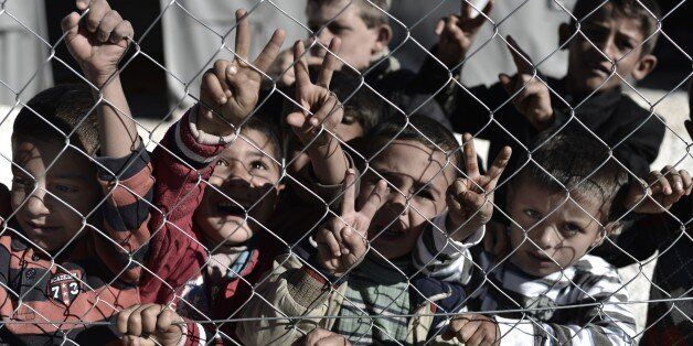 Young Syrian Kurdish boys make the 'V for victory' sign behind a fence at a refugee camp in the town of Suruc, Sanliurfa province, on November 5, 2014. Iraqi Kurdish peshmerga fighters who joined the battle for the Syrian border town of Kobane have been heavily shelling Islamic State group jihadists, a commander told AFP. AFP PHOTO / ARIS MESSINIS (Photo credit should read ARIS MESSINIS/AFP/Getty Images)