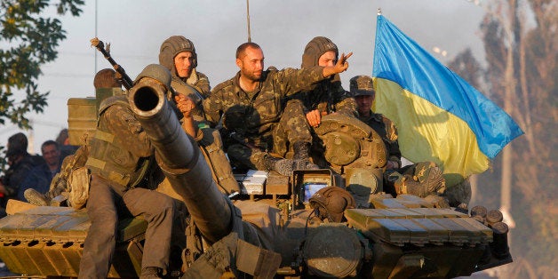 Soldiers of Ukrainian army ride on a tank in the port city of Mariupol, southeastern Ukraine, Friday, Sept. 5, 2014. The Ukrainian president declared a cease-fire Friday to end nearly five months of fighting in the nation's east after his representatives reached a deal with the Russian-backed rebels at peace talks in Minsk. (AP Photo/Sergei Grits)