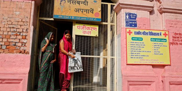 Indian women walk past a billboard advocating sterilization hung at the entrance of the District Womenâs Hospital in Varanasi, India, Wednesday, Nov. 12, 2014. At least a dozen women died this week following a state-run, mass sterilization program that has raised serious ethical questions about India's drive to curb a booming population by paying women to undergo tubectomies. India has one of the world's highest rates of sterilization among women, with about 37 percent undergoing such operations compared with 29 percent in China, according to 2006 statistics reported by the United Nations. About 4.6 million Indian women were sterilized in 2011 and 2012, according to the government. (AP Photo/Rajesh Kumar Singh)