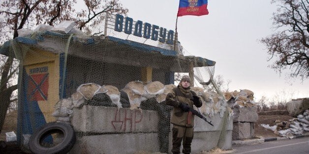 A pro-Russian gunman stands guard at a checkpoint with a Russian flag near Kharzisk, East of Donetsk, on November 16, 2014. Western nations sent a firm message to Russia at this weekend's G20 summit that it must stop its 'unacceptable' meddling in Ukraine or face further sanctions, British Prime Minister David Cameron said on November 16. AFP PHOTO/MENAHEM KAHANA (Photo credit should read MENAHEM KAHANA/AFP/Getty Images)