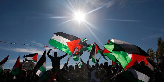 Palestinians wave flags as they celebrate their successful bid to win U.N. statehood recognition in the West Bank city of Ramallah, Sunday, Dec. 2, 2012. The Palestinian President Mahmoud Abbas, not shown, has returned home to a hero's welcome after winning a resounding endorsement for Palestinian independence at the United Nations. Israel on Sunday roundly rejected the United Nations' endorsement of an independent state of Palestine, announcing it would withhold more than $100 million collected for the Palestinian government to pay debts to Israeli companies. (AP Photo/Majdi Mohammed)