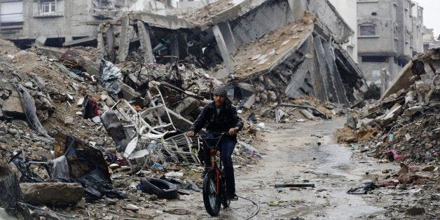 A Palestinian rides his bike past houses that were destroyed during the 50-day Gaza war between Israel and Hamas-led militant
