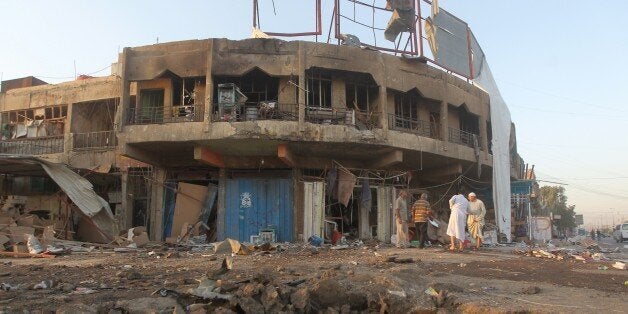 Iraqi men inspect the site of a car bomb explosion that killed over 7 people and wounded dozens in the neighbourhood of Ur