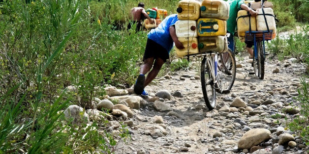 LA PARADA, COLOMBIA - MAY 2: Smugglers push bicycles loaded with gasoline barrels on the shore of the river Tachira on the Colombia-Venezuela border, on 2 May 2006 in La Parada, Colombia. Venezuelan gasoline, being 20 times cheaper than in Colombia, is the most wanted smuggling item, followed by food and car parts, while reputable Colombian clothing flow to Venezuela. There are about 25,000 barrels of gasoline crossing illegally the Venezuelan border every day. The risky contraband smuggling, especially during the rainy season when the river rises, makes a living to hundreds of poor families in communities on both sides of the frontier. (Photo by Jan Sochor/Latincontent/Getty Images)