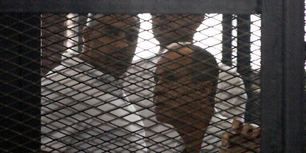 CAIRO, EGYPT - JUNE 23: An Egyptian court on Monday, June 23, handed out jail terms ranging from three to ten years each to 18 people, including four foreign Al Jazeera journalists convicted of 'fabricating news', eleven defendants including three foreign correspondents including Egyptian-Canadian Mohamed Fadel Fahmy (L), were sentenced in absentia to ten years each in jail. Seven others, including Australian Al Jazeera journalist Peter Greste (R), were sentenced to seven years each. (Photo by Stringer/Anadolu Agency/Getty Images)