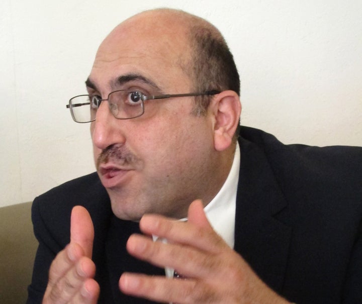 In this photo taken on Wednesday, Oct. 10, 2013, Rami Abdurrahman, gestures during an interview with The Associated Press in Coventry, England. He's practically a one man band, but Rami Abdurrahman's influence extends far beyond his modest home in this small English city. The bald, bespectacled 42-year-old operates the Syrian Observatory for Human Rights from his house in the cathedral city of Coventry â and a review of recent media coverage suggests its running tally of killings and clashes is the most frequently cited individual source of information on Syria's civil war for the world's leading news organizations. (AP Photo/Raphael Satter)