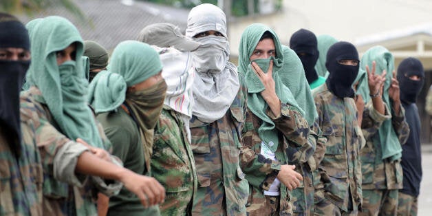 Members of 'Los Rastrojos' bandit group cover their face with towels and balaclavas as they surrender at the Voltigeros Battalion on May 21, 2009 in Uraba, Antioquia department, Colombia. 112 members of 'Los Rastrojos', a group of former AUC paramilitary right-wing guerrillas who became drug traffickers, have surrendered in Nuqui, Choco deparment, in the last days. AFP PHOTO / Raul ARBOLEDA (Photo credit should read RAUL ARBOLEDA/AFP/Getty Images)