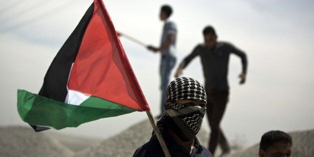 A Palestinian demonstrator holds the national flag during clashes near the border with Israel, east of Gaza City on May 15, 2014, to mark Nakba Day. Palestinians are marking 'Nakba day' which means in Arabic 'catastrophe' in reference to the birth of the state of Israel 66-years-ago in British-mandate Palestine, which led to the displacement of hundreds of thousands of Palestinians who either fled or were driven out of their homes during the 1948 war over Israel's creation. AFP PHOTO/MOHAMMED ABED (Photo credit should read MOHAMMED ABED/AFP/Getty Images)