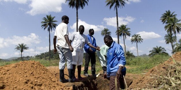 Health workers from Guinea's Red cross wearing Personal Protective Equipments (PPE) prepare to bury bodies of victims of the
