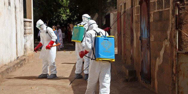 In this photo taken Friday, Nov. 14, 2014, health workers spray disinfectant around a mosque after the body of a man suspected of dying from the Ebola virus was washed inside before being berried in Bamako, Mali. It all started with a sick nurse, whose positive test results for Ebola came only after death. In a busy clinic that treats Bamakoâs elite as well as wounded U.N. peacekeepers, who was the patient who had transmitted the virus? Soon hospital officials were taking a second look at the case of a 70-year-old man brought to the capital late at night from Guinea suffering from kidney failure. On Friday, Malian health authorities went to disinfect the mosque where the 70-year-oldâs body was prepared for burial - nearly three weeks ago. Already some are criticizing the government for being too slow to react when health authorities had announced his death as a suspected Ebola case earlier in the week.(AP Photo/Baba Ahmed)