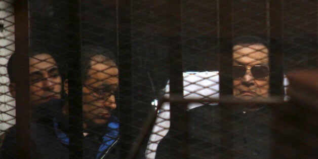 Ousted Egyptian President Hosni Mubarak, 86, lies on a gurney, next to his son Gamal, second left, in the defendants cage, during a court hearing in Cairo, Egypt, Saturday, Nov. 29, 2014. An Egyptian court on Saturday dismissed murder charges against former president Hosni Mubarak in connection with the killing of protesters in the 2011 uprising that ended his nearly three-decade reign. Saturday's verdict concludes Mubarak's retrial along with his two sons, his security chief and six top security commanders, who were all acquitted. (AP Photo/Tarek el-Gabbas)