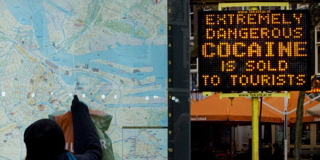 A tourists points at a map next to an electronic sign post warning of extremely dangerous cocaine being sold on Rembrandtplei