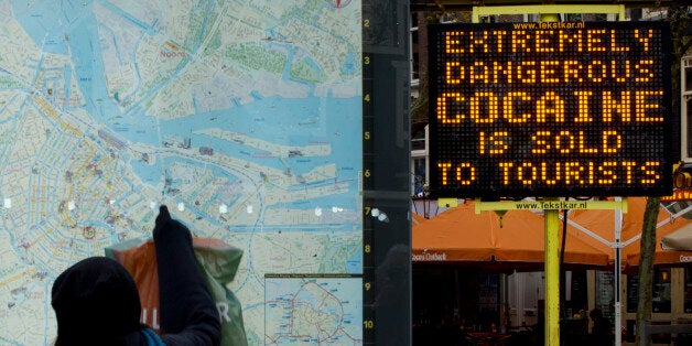 A tourists points at a map next to an electronic sign post warning of extremely dangerous cocaine being sold on Rembrandtplein square in the center of Amsterdam, Netherlands, Thursday, Nov. 27, 2014. Health authorities in Amsterdam are warning tourists after three British men died in the last month after snorting heroin they may have believed was cocaine. (AP Photo/Peter Dejong)