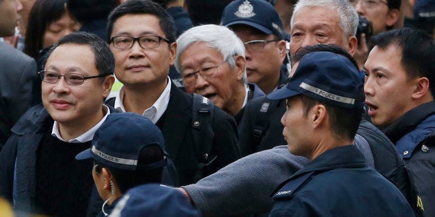 Four protest leaders, from left, Benny Tai Yiu-ting, Chan Kin-man, Joseph Zen and Chu Yiu-ming, surrounded by police officers, walk to the police station in Hong Kong as they surrender to police Wednesday, Dec. 3, 2014 to take responsibility for protests that have shut down parts of the Asian financial center for more than two months. Three founders of Hong Kong's pro-democracy protest movement called for an end to street demonstrations to prevent more violence and take the campaign to a new stage, but it wasn't clear whether student protesters, who make up the bulk of the activists, would heed the call. (AP Photo/Kin Cheung)