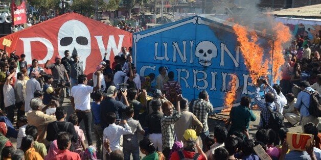 Indian residents and Bhopal Gas disaster survivors set alight a banner of Union Carbide as they commemorate the 30th anniversary of the disaster in Bhopal on December 3, 2014. Protesters in the Indian city of Bhopal burned effigies representing Dow Chemicals and displayed placards demanding justice as they marked the 30th anniversary December 2 of the world's deadliest industrial disaster. Some held old black and white photographs of loved ones lost on the night of December 2, 1984, when a cloud of highly toxic methyl isocyanate gas spewed from a Union Carbide factory in Bhopal and blew across the city. AFP PHOTO (Photo credit should read STR/AFP/Getty Images)