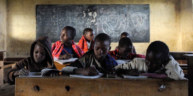 Kelvin Leadismo (2nd L), 12, and his classmates attend a tuition class at Loltulelei primary school on July 16, 2013 in Kisima township of Kenya's nothern county of Samburu. The class is attended by young shepherds from the Samburu community who are usually unable to attend regular daytime classes when they are tending to their family's livestock at pasture. The school runs a parallel tuition programme to the national curriculum that enables the otherwise illeterate shepherds acquire literacy through the two to three hour tuition courses presided over by volunteer teachers. AFP PHOTO / Tony KARUMBA (Photo credit should read TONY KARUMBA/AFP/Getty Images)