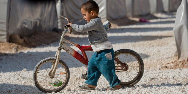 A Syrian Kurdish refugee child from the Kobani area walks with a bicycle at a camp in Suruc, on the Turkey-Syria border Tuesday, Nov. 18, 2014. Kobani, also known as Ayn Arab, and its surrounding areas, has been under assault by extremists of the Islamic State group since mid-September and is being defended by Kurdish fighters. (AP Photo/Vadim Ghirda)