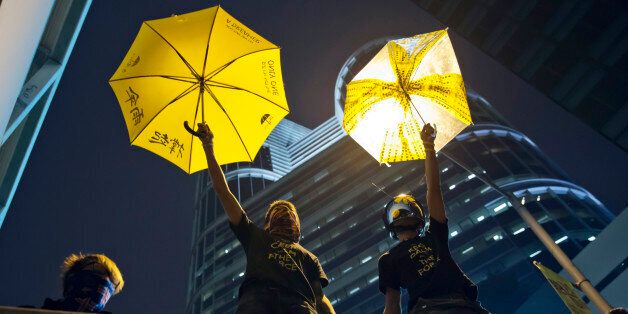 Protesters pose for photographs on a barricade at the occupied area outside government headquarters in Hong Kong Wednesday, Dec. 10, 2014. Hong Kong's dwindling number of pro-democracy protesters vowed Wednesday to stay until the last minute before authorities clear them off a highway where they've been camped out for more than two months. (AP Photo/Kin Cheung)