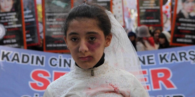 A Turkish girl, wearing a wedding dress and covered with fake bruises, stands in front of other protesters holding placard reading '' end violence'' during a demonstration to protest against rape, killings and domestic violence against women, in Ankara on November 27, 2011. AFP PHOTO/ADEM ALTAN (Photo credit should read ADEM ALTAN/AFP/Getty Images)