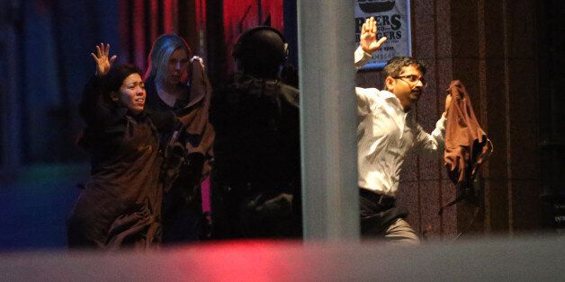 Hostages run to safety during a cafe siege in the central business district of Sydney , Australia, Tuesday, Dec. 16, 2014. A swarm of heavily armed police stormed a cafe in the heart of downtown Sydney early Tuesday, ending a siege where a gunman had been holding an unknown number of people hostage for more than 16 hours. A police spokesman confirmed "the operation is over," but would not release any further details about the fate of the gunman or his remaining captives. After a flurry of loud bangs, police swooped into the Lindt Chocolat Cafe shortly after five or six hostages were seen running from the building. (AP Photo/Rob Griffith)