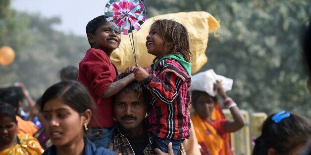 A boy and girl smile as they play with their windwheels in a country road leading away from the village of Barayarpur after they and their families participated in the Gadhimai festival on November 28, 2014. Millions of Hindu devotees from Nepal and India migrate to the village to honour their goddess of power. The celebrations includes the slaughtering of hundreds of thousands of animals, mostly buffalo and goats. Worshippers from Nepal and neighbouring India have spent days sleeping out in the open and offering prayers to the goddess at a temple decked with flowers in preparation. AFP PHOTO/ROBERTO SCHMIDT (Photo credit should read ROBERTO SCHMIDT/AFP/Getty Images)