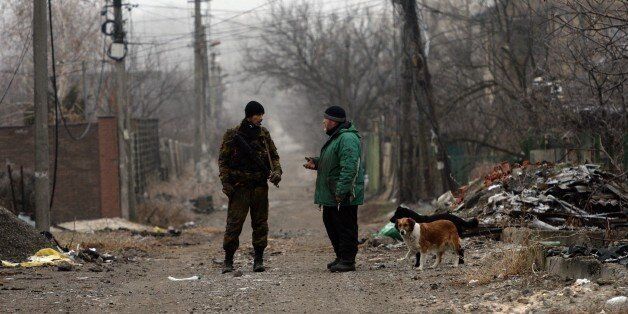 An armed supporter of self-proclamed People's Republic of Donetsk speaks with a local resident on the street among the destroyed houses in the airport area in eastern Ukrainian city of Donetsk on December 16, 2014. AFP PHOTO / VASILY MAXIMOV (Photo credit should read VASILY MAXIMOV/AFP/Getty Images)