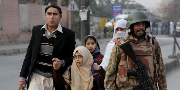 Pakistani parents escort their children outside a school attacked by THE Taliban in Peshawar, Pakistan, Tuesday, Dec. 16, 2014. Taliban gunmen stormed a military-run school in the northwestern Pakistani city of Peshawar on Tuesday, killing and wounding scores, officials said, in the highest-profile militant attack to hit the troubled region in months. (AP Photo/B.K. Bangash)