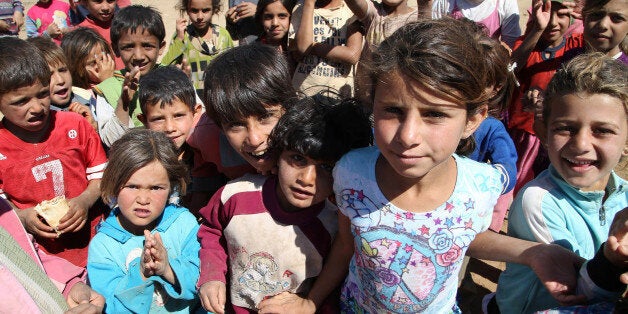 In this picture taken on Tuesday, Sept. 16, 2014, Displaced Syrian boys and girl gather at their refugee camp during the visit of the United Nations High Commissioner for Refugees (UNHCR) Antonio Guterres and U.N. Development Program Administrator Helen Clark, in Deir al-Ahmar village, near Baalbek city, east Lebanon. A report by the Britain-based Save the Children released Thursday, Sept. 18, 2014 says that nearly three million Syrian children are not attending school due to the war raging in their country. (AP Photo/Hussein Malla)