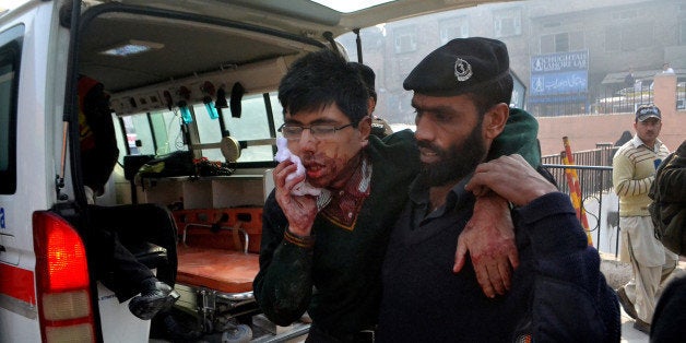 A hospital security guard helps a student injured in the shootout at a school under attack by Taliban gunmen in Peshawar, Pakistan,Tuesday, Dec. 16, 2014. Taliban gunmen stormed a military school in the northwestern Pakistani city, killing and wounding dozens, officials said, in the latest militant violence to hit the already troubled region. (AP Photo/Mohammad Sajjad)