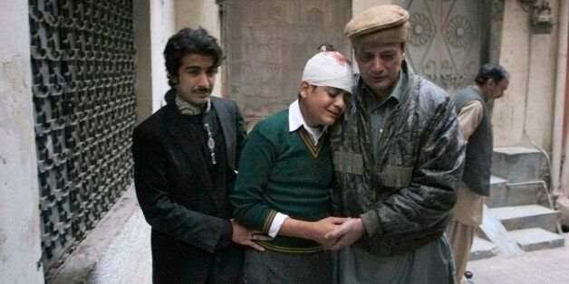 The uncle and cousin of injured student Mohammad Baqair, center, comfort him as he mourns the death of his mother who was a teacher at the school which was attacked by Taliban, in Peshawar, Pakistan, Tuesday, Dec. 16, 2014. Taliban gunmen stormed a military-run school in the northwestern Pakistani city of Peshawar on Tuesday, killing more than 100, officials said, in the highest-profile militant attack to hit the troubled region in months. (AP Photo/Mohammad Sajjad)