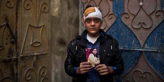 Pakistani student, Mohammad Baqair, who survived last Tuesday's Taliban attack on a military-run school and was slightly injured, poses for a picture holding a photograph of his mother a victim of the attack, who was a teacher at the school, at his home, in Peshawar, Pakistan, Thursday, Dec. 18, 2014. The Taliban massacre that killed more than 140 people, mostly children, at a military-run school in northwestern Pakistan left a scene of heart-wrenching devastation, pools of blood and young lives snuffed out as the nation mourned and mass funerals for the victims got underway. (AP Photo/Muhammed Muheisen)
