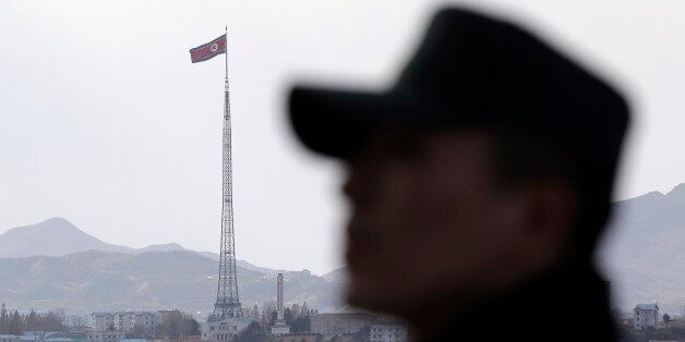 In this Wednesday, Nov. 12, 2014 photo, a South Korean soldier stands as a North Korean flag flies atop a 160-meter (533-foot) tower in the village of Gijungdong, near the North side of the border village of Panmunjom, which has separated the two Koreas since the Korean War, north of Seoul, South Korea. North Korea threatened Thursday, Nov. 20, 2014 to bolster its war capability and conduct a fourth nuclear test to cope with what it calls U.S. hostility that led to the approval of a landmark U.N. resolution on its human rights violations. (AP Photo/Lee Jin-man)
