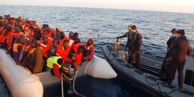 In this photo released by the Italian Navy Thursday, March 20, 2014, migrants stand on a dinghy after being rescued along the
