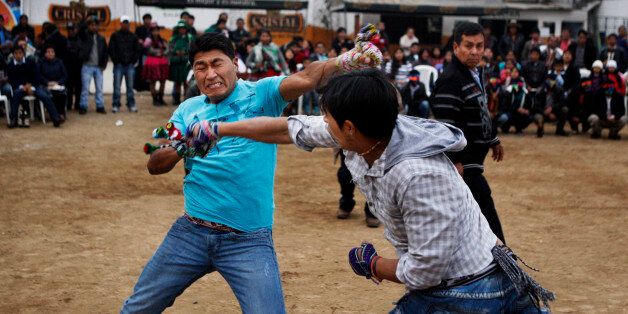 In this July 14, 2013 photo, Eloy Luna, left, and Rony Garate fight during a Takanakuy ritual fight in Lima, Peru. When the brightly hued ski masks come off, the punching and kicking begin. Only once a judge has ruled one of the combatants licked do they stop fighting. (AP Photo/Karel Navarro)
