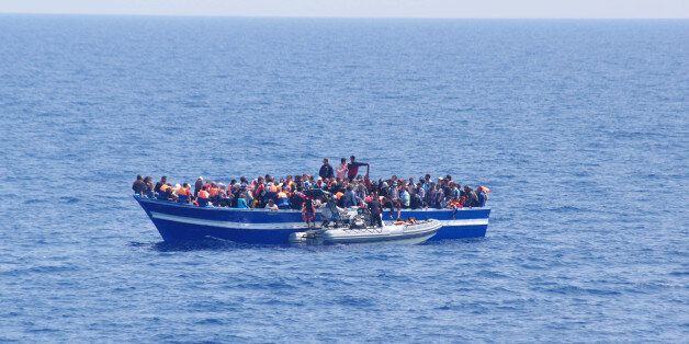 In this photo released by the Italian Navy on Sunday, June 15, 2014, and taken on Saturday, June 14, 2014, a boat filled with migrants receives aid from an Italian Navy motor boat off the coast of Sicily, Italy. The Italian coast guard and navy have rescued more than 300 migrants whose boats ran into trouble in the Mediterranean Sea and recovered the bodies of 10 migrants whose dinghy had overturned. Naval official Salvatore Scimone said 39 survivors on Saturday had grabbed onto the dinghy until rescuers plucked them to safety aboard another boat. He said he feared that an undetermined number of others were missing in the sea north of Libya. In a separate rescue, three Italian ships took aboard 281 migrants who said they were Syrian and whose fishing boat ran into problems. (AP Photo/Italian Navy, ho)