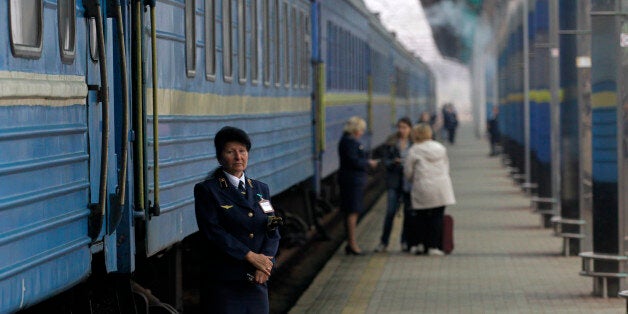 A Ukrainian railways employee stands in front of a first train departing from the Donetsk to Sevastopol, Crimea at Donetsk's railway station, eastern Ukraine, Thursday, Sept. 25, 2014. A direct railway link between Donetsk and Sevastopol that was halted by war has resumed today. (AP Photo/Darko Vojinovic)