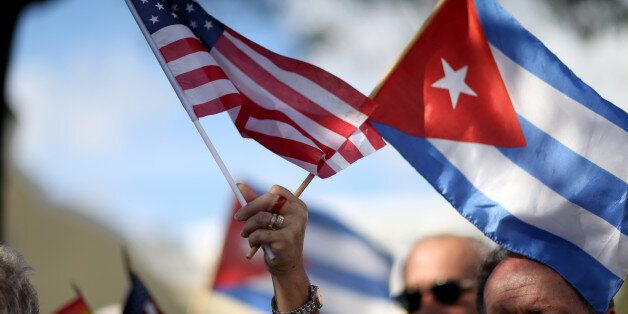 MIAMI, FL - DECEMBER 20: A protester holds an American flag and a Cuban one as she joins with others opposed to U.S. President Barack Obama's announcement earlier in the week of a change to the United States Cuba policy stand together at Jose Marti park on December 20, 2014 in Miami, Florida. President Obama announced a move toward normalizing the relationship with Cuba after a swap of prisoners took place. (Photo by Joe Raedle/Getty Images)