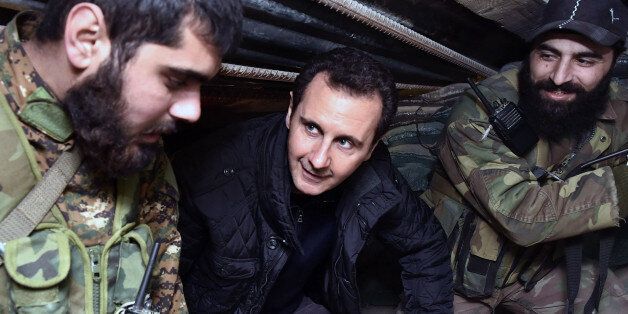 In this Wednesday, Dec. 31, 2014 photo released by the Syrian official news agency SANA, Syrian President Bashar Assad, center, speaks with Syrian troops during his visit to the front line in the eastern Damascus district of Jobar, Syria. Assad has made a rare visit to the frontline spending New Yearâs Eve with his troops in a tense eastern Damascus neighborhood. (AP Photo/SANA)
