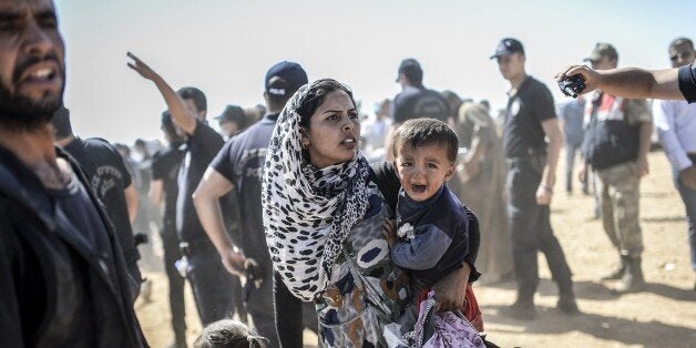 A Syrian Kurdish woman crosses the border between Syria and Turkey at the southeastern town of Suruc in Sanliurfa province on September 23, 2014. The UN refugee agency warned Tuesday that as many as 400,000 people may flee to Turkey from Syria's Kurdish region to escape attacks by the Islamic State group. AFP PHOTO / BULENT KILIC (Photo credit should read BULENT KILIC/AFP/Getty Images)