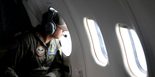 A crew member of Indonesian Navy's CN-235 transport plane looks out of a window during a search operation for victims of the