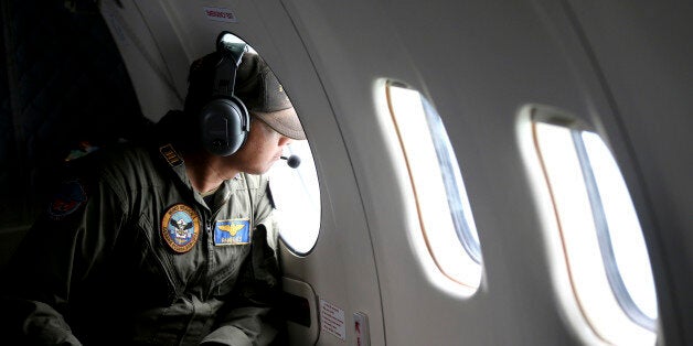 A crew member of Indonesian Navy's CN-235 transport plane looks out of a window during a search operation for victims of the ill-fated AirAsia Flight 8501 on Java Sea, Indonesia, Thursday, Jan. 1, 2015. The weather improved as the search resumed Thursday for the victims with officials trying to locate the fuselage of the plane that crashed in the sea four days ago. (AP Photo/Tatan Syuflana)