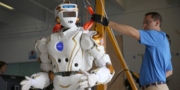 HOMESTEAD, FL - DECEMBER 21: Court Edmondson works on the team NASA robot during the DARPA Robotics Challenge Trials at the Homestead-Miami Speedway on December 21, 2013 in Homestead, Florida. The trials put prototype robots from seventeen teams through a series of simple tasks such as opening doors or walking a short distance. The competition is hoping to speed development of robots that could perform a number of critical real-world emergency-response tasks. (Photo by Joe Raedle/Getty Images)