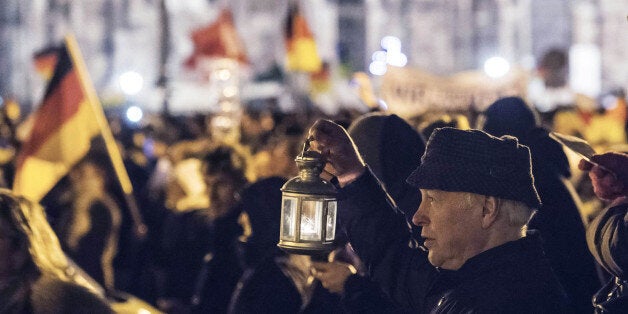 A participant of a rally called 'Patriotic Europeans against the Islamization of the West' (PEGIDA) holds a hand lantern and sings during a demonstration entitled âChristmas With Pegidaâ between the bronze equestrian statue of King John of Saxony, left, and the Dresden Cathedral, or the Cathedral of the Holy Trinity, in Dresden, eastern Germany, Monday, Dec. 22, 2014. For the past ten weeks, activists protesting Germanyâs immigration policy and the spread of Islam in the West have been marching each Monday. (AP Photo/Jens Meyer)