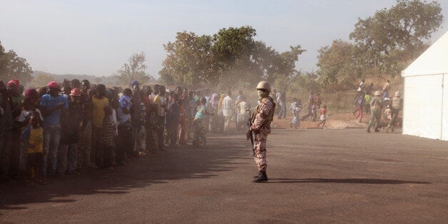 In this photo taken Monday, Nov. 17, 2014, a Mali soldier, center, controls a crowd of people during a visit by their president, Ibrahim Boubacar Keita, at the border village of Kouremale, Mali, between Mali and Guinea. On Mali's dusty border with Ebola-stricken Guinea, travelers have a new stop: Inside a white tent, masked medical workers zap incomers with infrared thermometer guns and instruct them to wash their hands in chlorinated water. (AP Photo/Baba Ahmed)