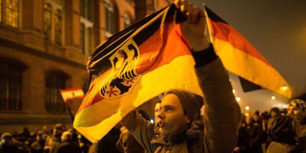 BERLIN, GERMANY - JANUARY 05: A supporter of the Pegida movement holds a flag while supporters gather for a march in their f