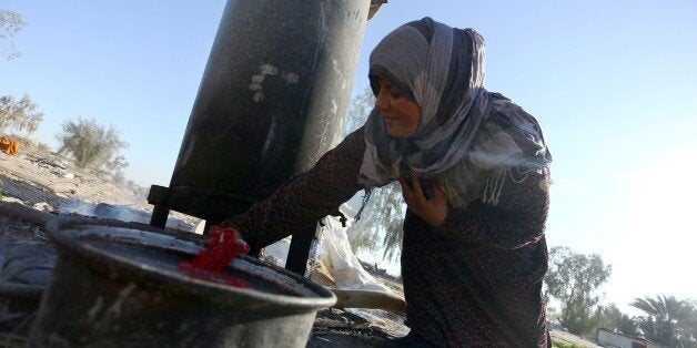 An Iraqi woman displaced by fighting, between government supporters and the Islamic State (IS) group, uses hot water to wash