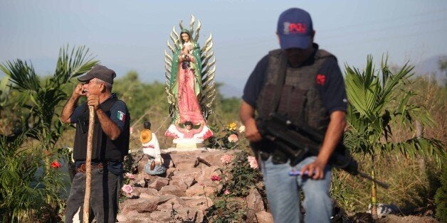 A policeman stands guard at the crime scene after 11 people were killed in La Ruana, Michoacan state, Mexico on December 17, 2014. Mexican vigilante groups fighting drug cartels turned on each other Tuesday in a shoot out that left at least 11 dead, officials said. AFP PHOTO/STR (Photo credit should read STR/AFP/Getty Images)