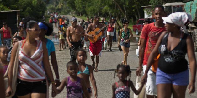 In this Aug 17, 2014, photo, people walk towards the beach after leaving the train that brought them from the capital to a nearby beach of Havana, Cuba. Many Cubans take the special summer train from Havana to the beach in Guanabo, east of the capital. (AP Photo/Ramon Espinosa)
