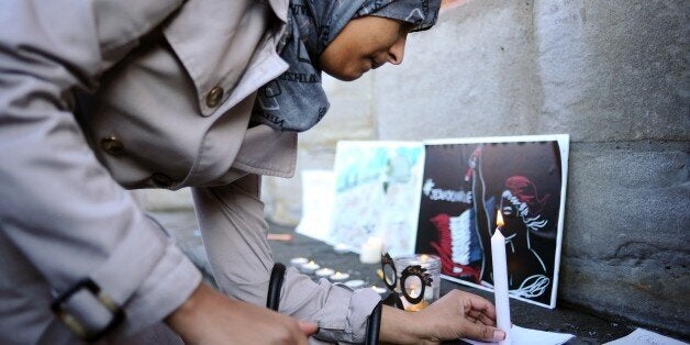 A woman places a candle in front of the city hall in Toulouse, on January 8, 2015, a day after Islamist gunmen stormed the office of French satirical newspaper Charlie Hebdo, killing eight journalists, two police and two others. French security forces desperately hunted two brothers Thursday suspected of gunning down 12 people in an Islamist attack on a satirical weekly, as a stunned and outraged France fell silent to mourn the victims. With thousands of police scouring France after the bloodiest attack in the country for half a century, the two men -- still armed -- were apparently spotted at a petrol station in the northern Aisne region. AFP PHOTO / REMY GABALDA (Photo credit should read REMY GABALDA/AFP/Getty Images)